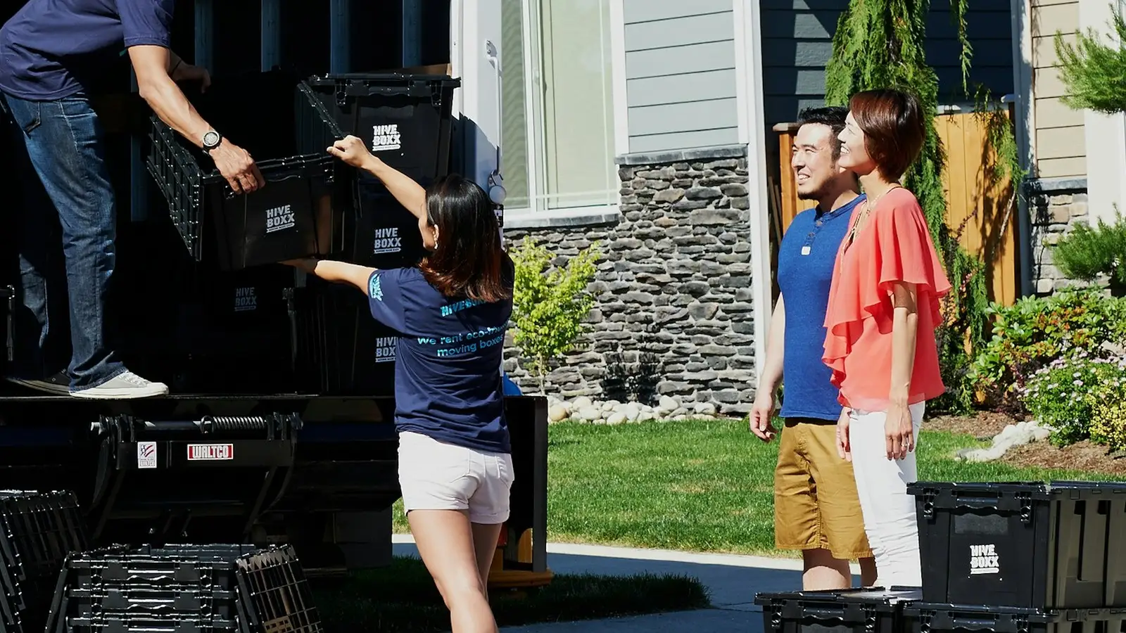 Moving crew unloading stacked crates outside a house on moving day